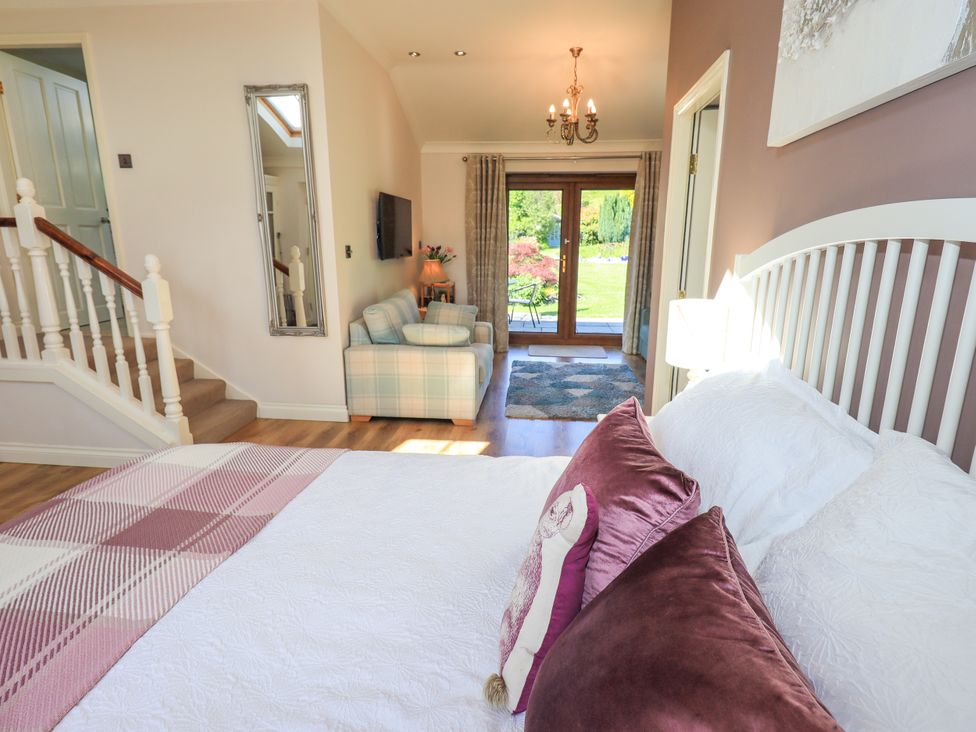 A bedroom with a bed, sofa, and door leading to outdoor area at The Garden Suite at Fiddler Hall Barn, Newby Bridge