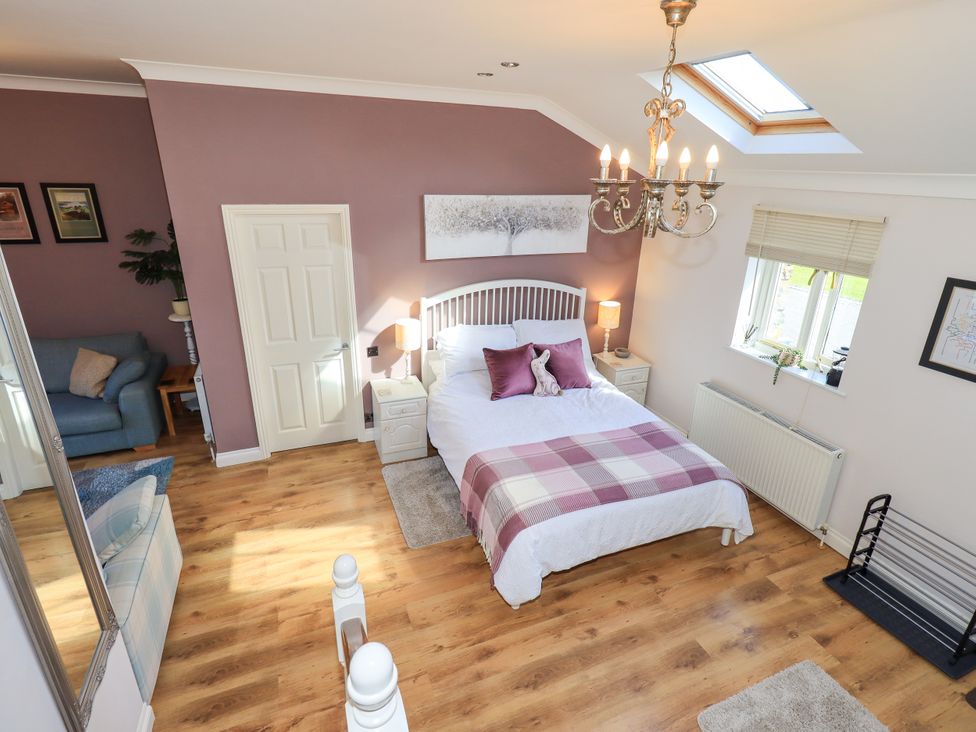 A bedroom with a bed and nightstands at The Garden Suite at Fiddler Hall Barn, Newby Bridge