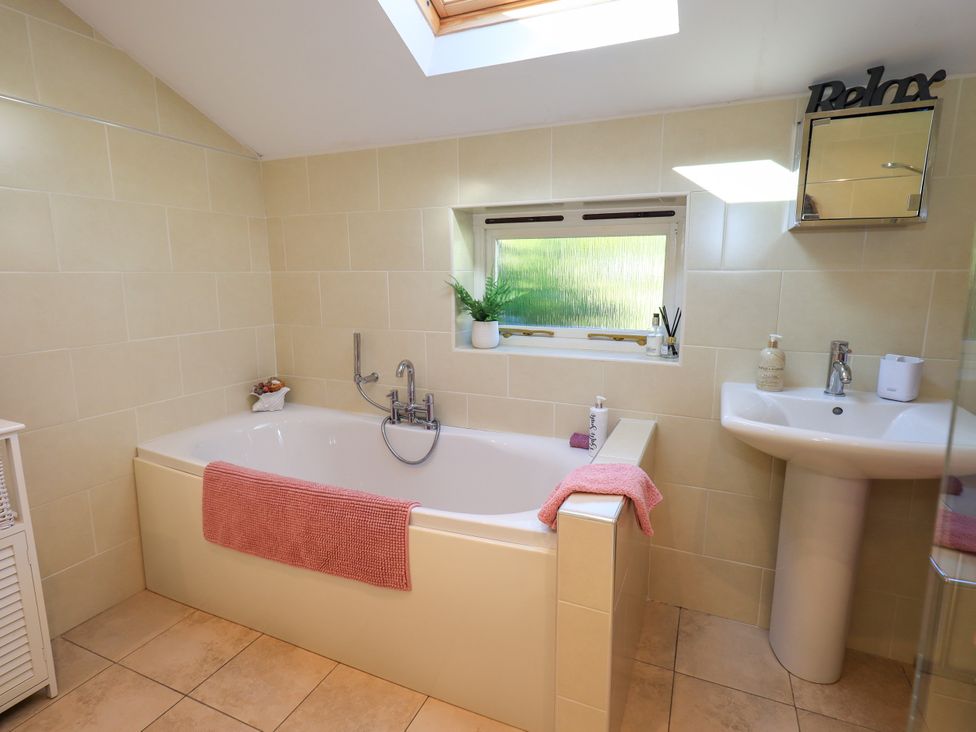 A bathroom with a bathtub and sink at The Garden Suite at Fiddler Hall Barn Newby Bridge