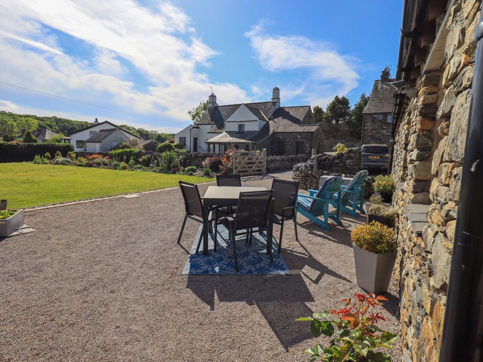 A garden with seating area and stone house at The Garden Suite at Fiddler Hall Barn Newby Bridge
