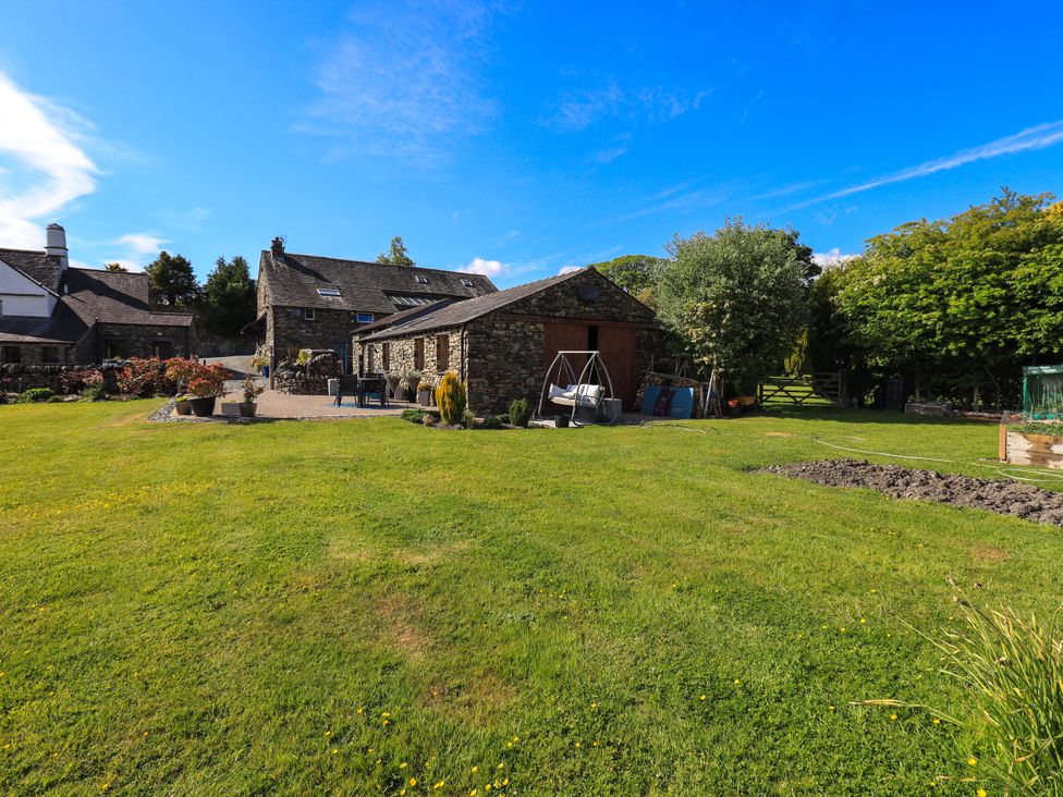 An outdoor view of buildings and garden space at The Garden Suite at Fiddler Hall Barn Newby Bridge