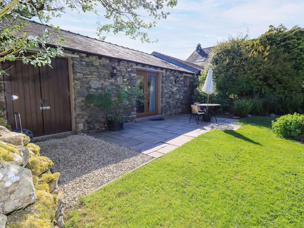 A garden with a stone patio and table at The Garden Suite at Fiddler Hall Barn in Newby Bridge