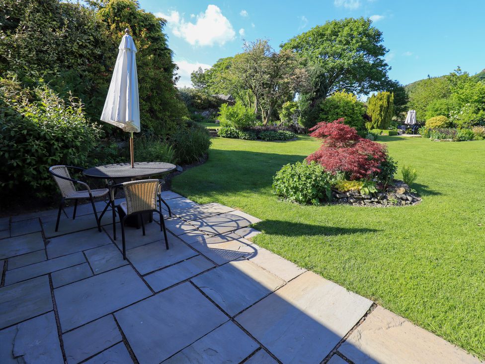 A garden with a table and chairs under an umbrella at The Garden Suite at Fiddler Hall Barn, Newby Bridge