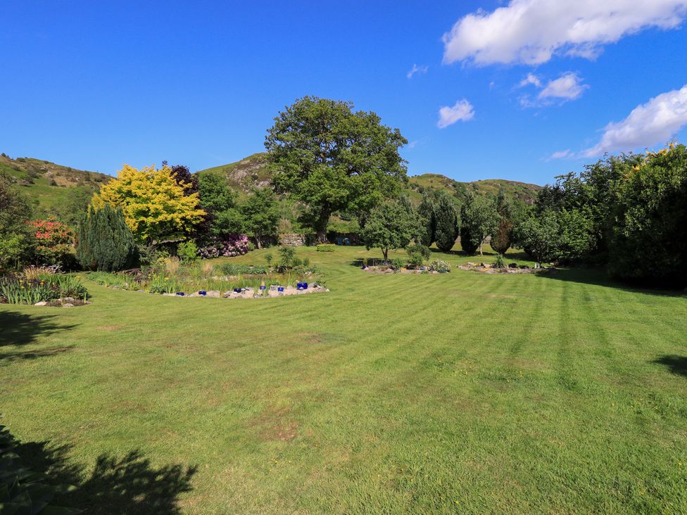 A garden with trees and flower beds at The Garden Suite at Fiddler Hall Barn Newby Bridge