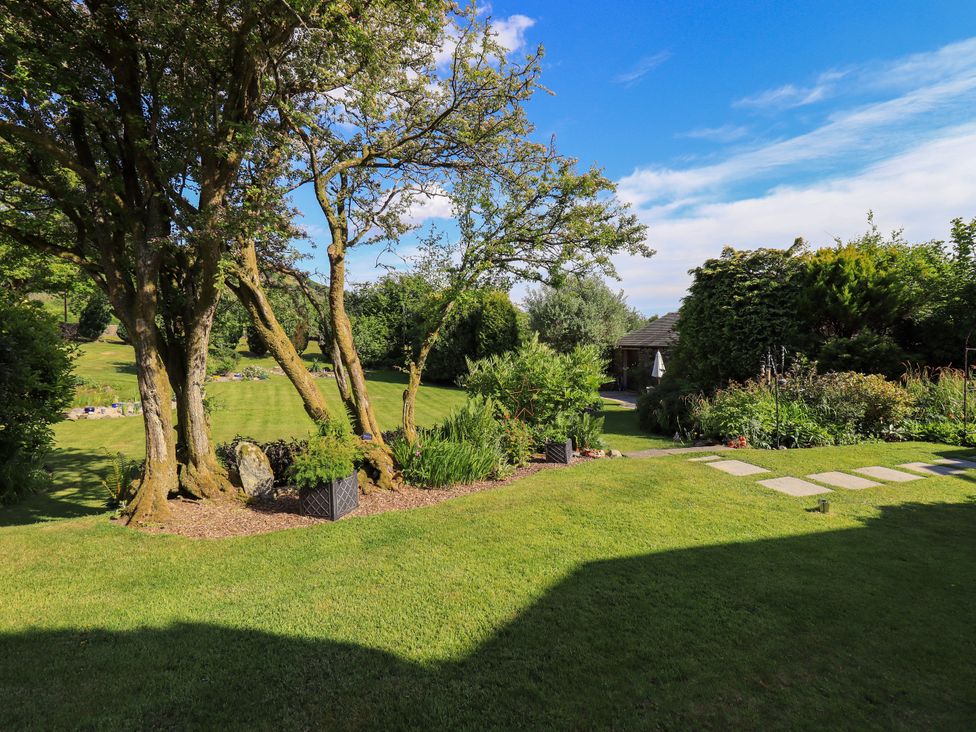 A garden with trees and flower beds at The Garden Suite at Fiddler Hall Barn Newby Bridge