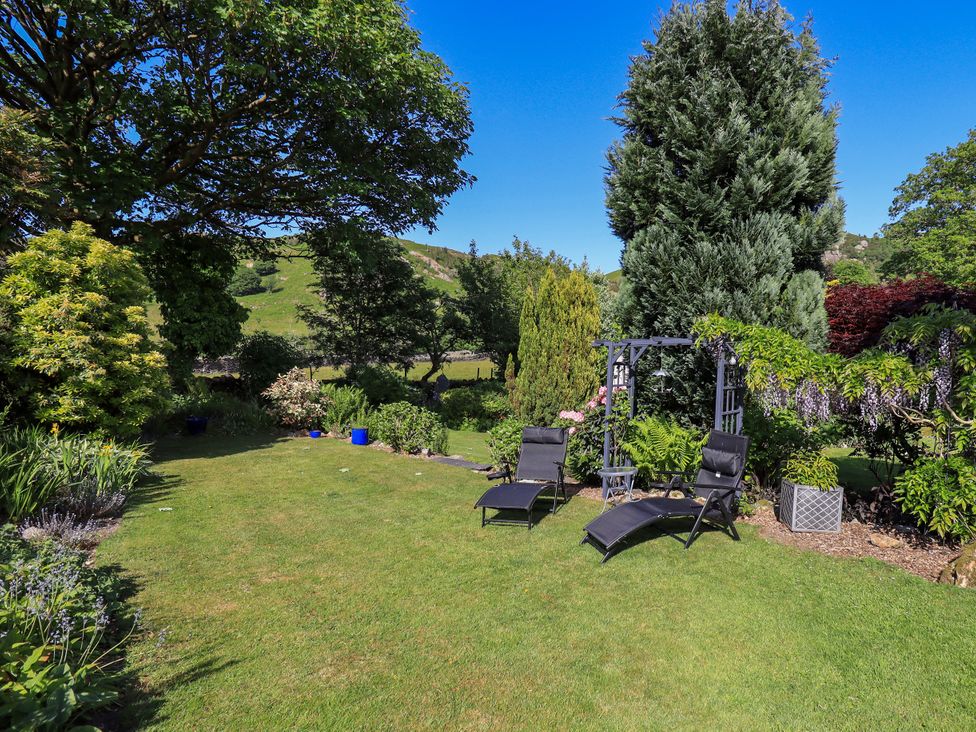 A garden with lounge chairs and trees at The Garden Suite at Fiddler Hall Barn Newby Bridge
