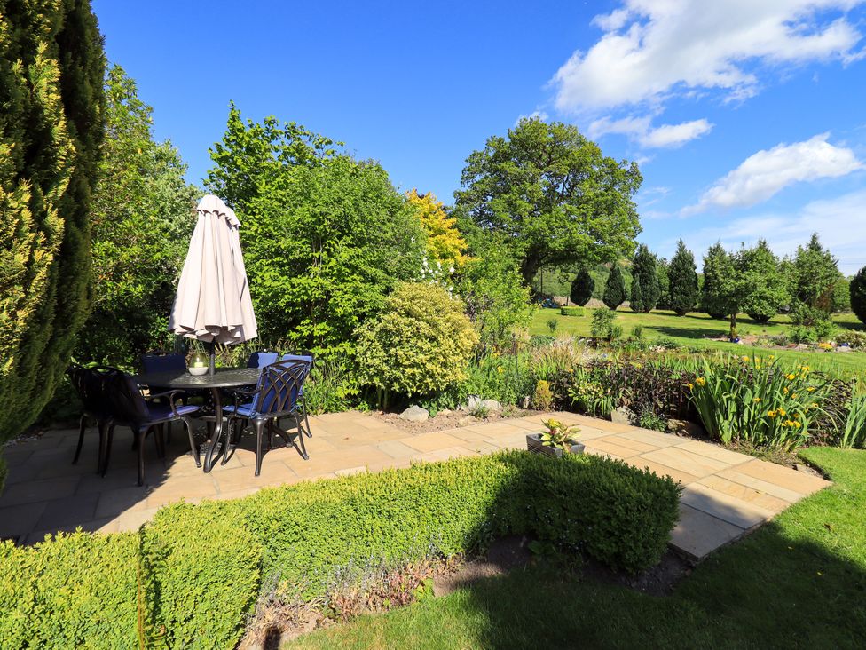 A garden with a table and chairs under an umbrella at The Garden Suite at Fiddler Hall Barn Newby Bridge