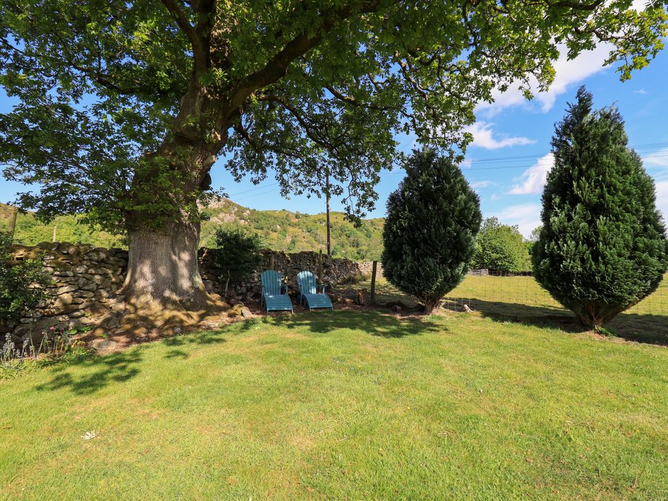 A garden with chairs and a tree at The Garden Suite at Fiddler Hall Barn Newby Bridge