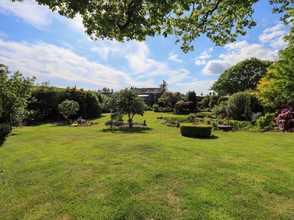 A garden with trees and flower beds at The Garden Suite at Fiddler Hall Barn Newby Bridge