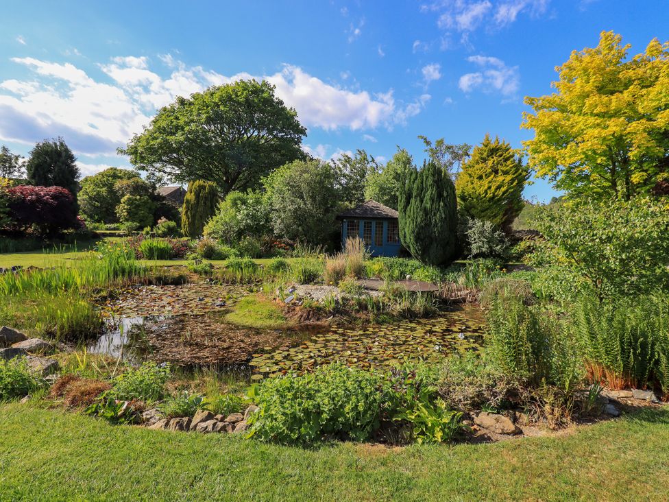 A garden with a pond and a shed at The Garden Suite at Fiddler Hall Barn Newby Bridge