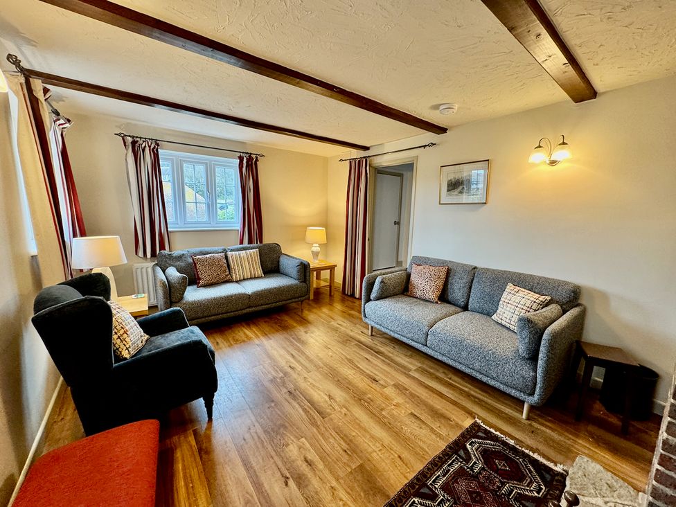 A living room with sofas and a lamp at Cajun Cottage in West Lulworth