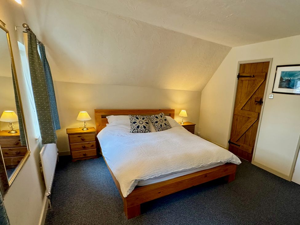 A bedroom with a bed and bedside tables at Cajun Cottage in West Lulworth