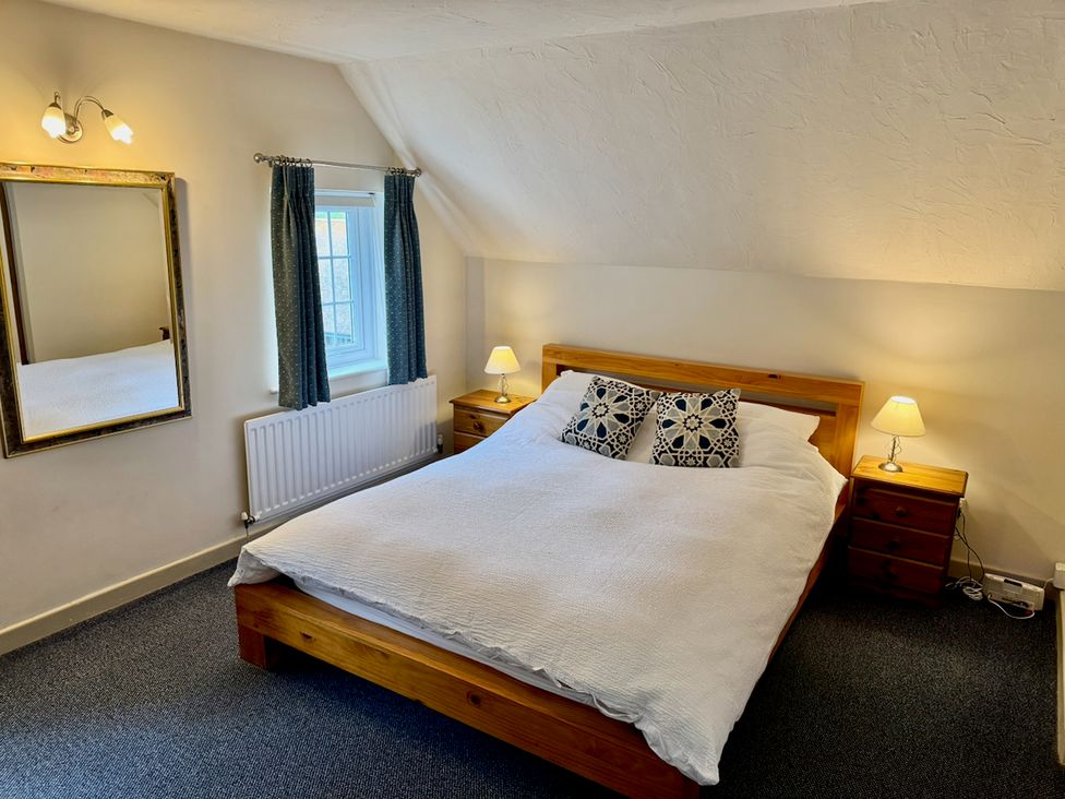 A bedroom with a bed and bedside tables at Cajun Cottage in West Lulworth