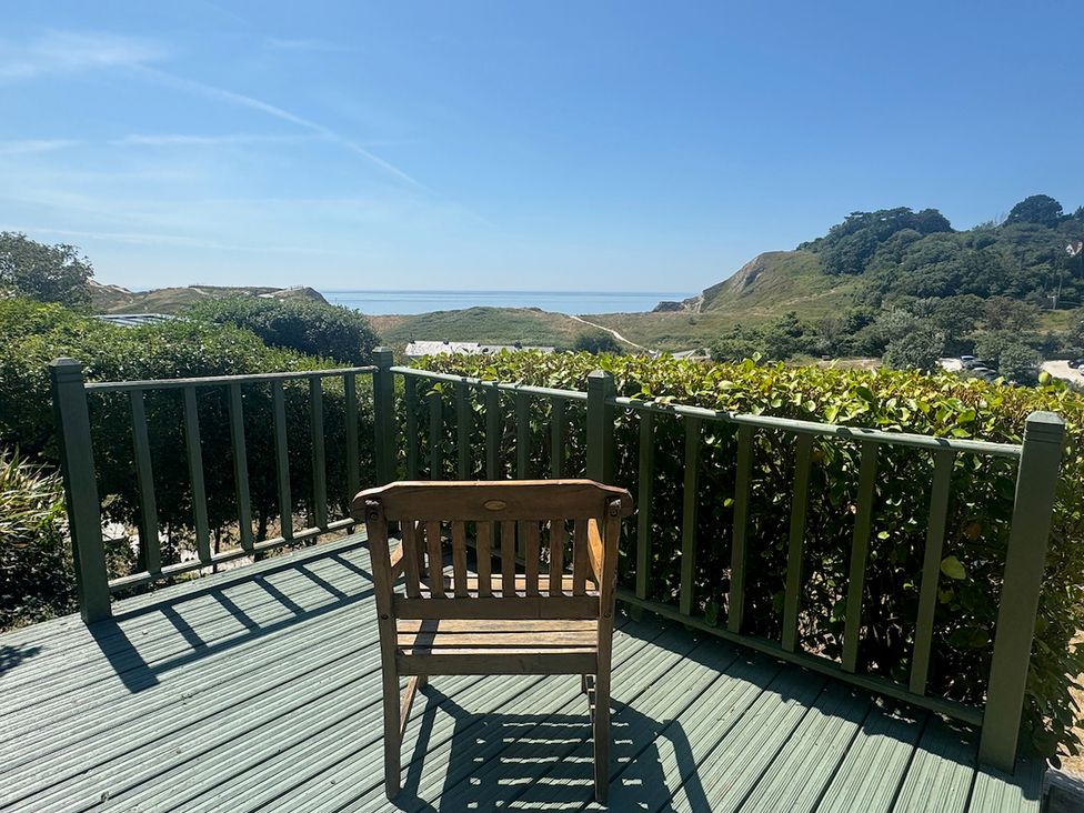 A chair on a deck overlooking the ocean at Cajun Cottage in West Lulworth