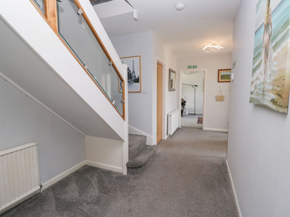 A hallway with a staircase and wall art at Eildon Lodge in Gosforth