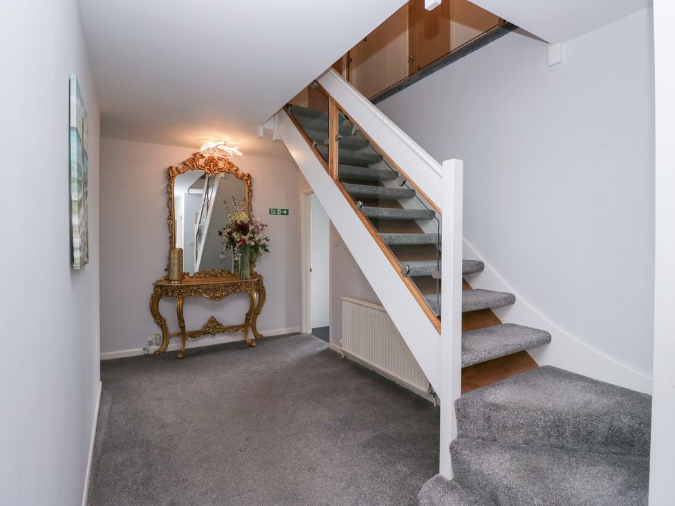 A hallway with a staircase and a console table with flowers at Eildon Lodge Gosforth