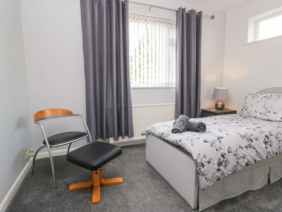 A bedroom with a bed, chair, and lamp at Eildon Lodge in Gosforth