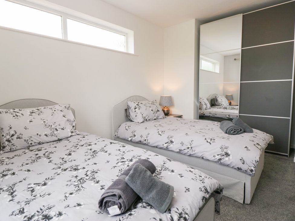 A bedroom with two beds and a wardrobe at Eildon Lodge in Gosforth