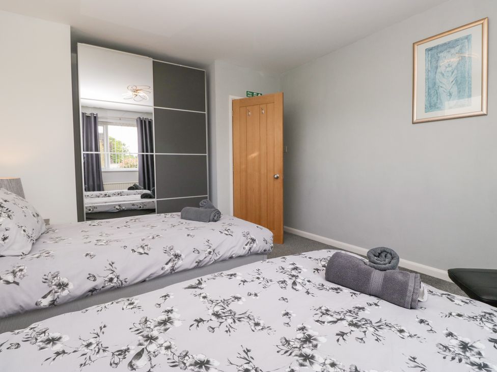 A bedroom with two beds and a large mirror at Eildon Lodge in Gosforth