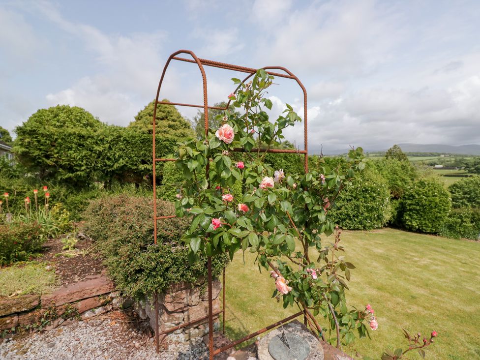 A garden with a rose trellis and flowers at Eildon Lodge in Gosforth