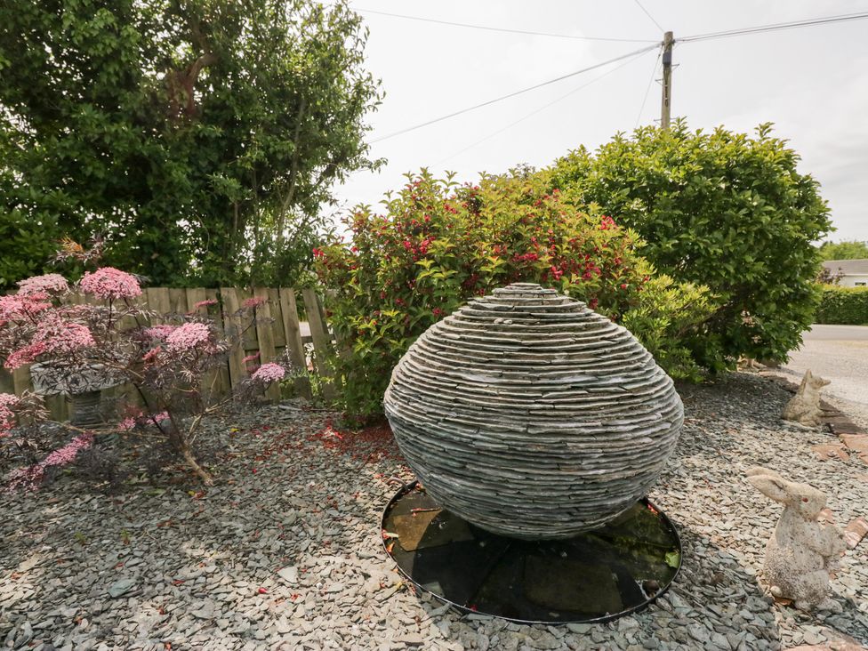 An outdoor garden with a stone sculpture surrounded by plants and gravel at Eildon Lodge in Gosforth