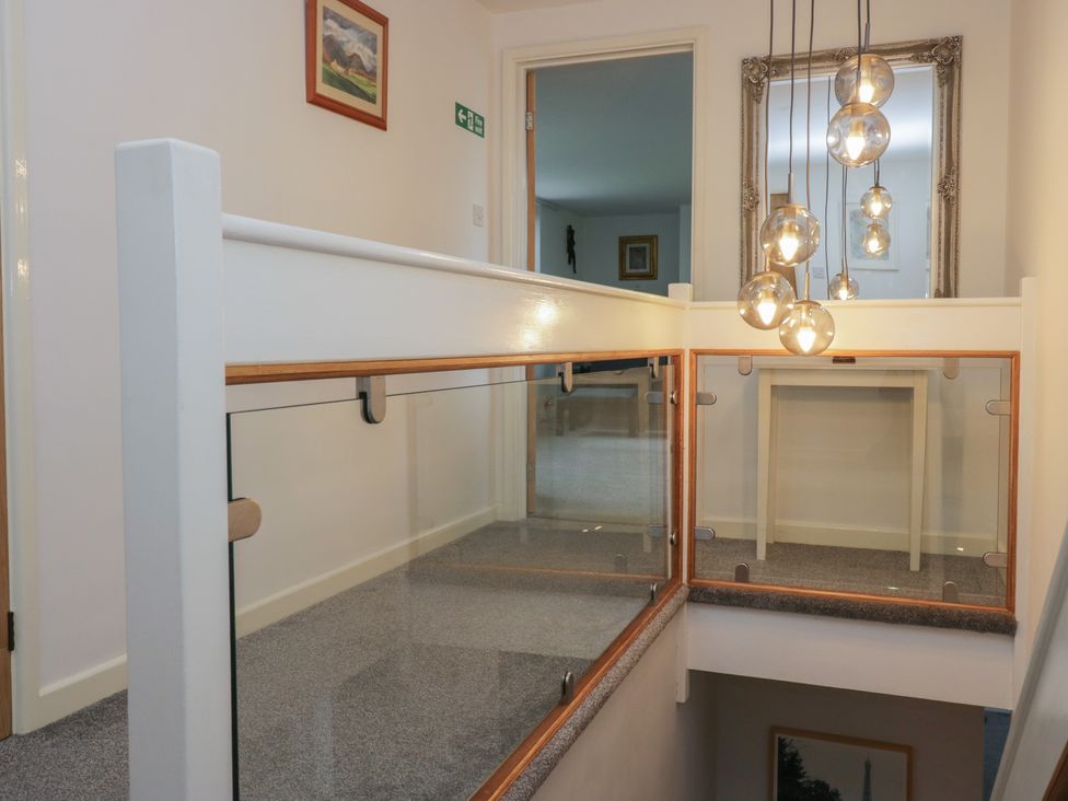A hallway with a balustrade and light fixtures at Eildon Lodge in Gosforth