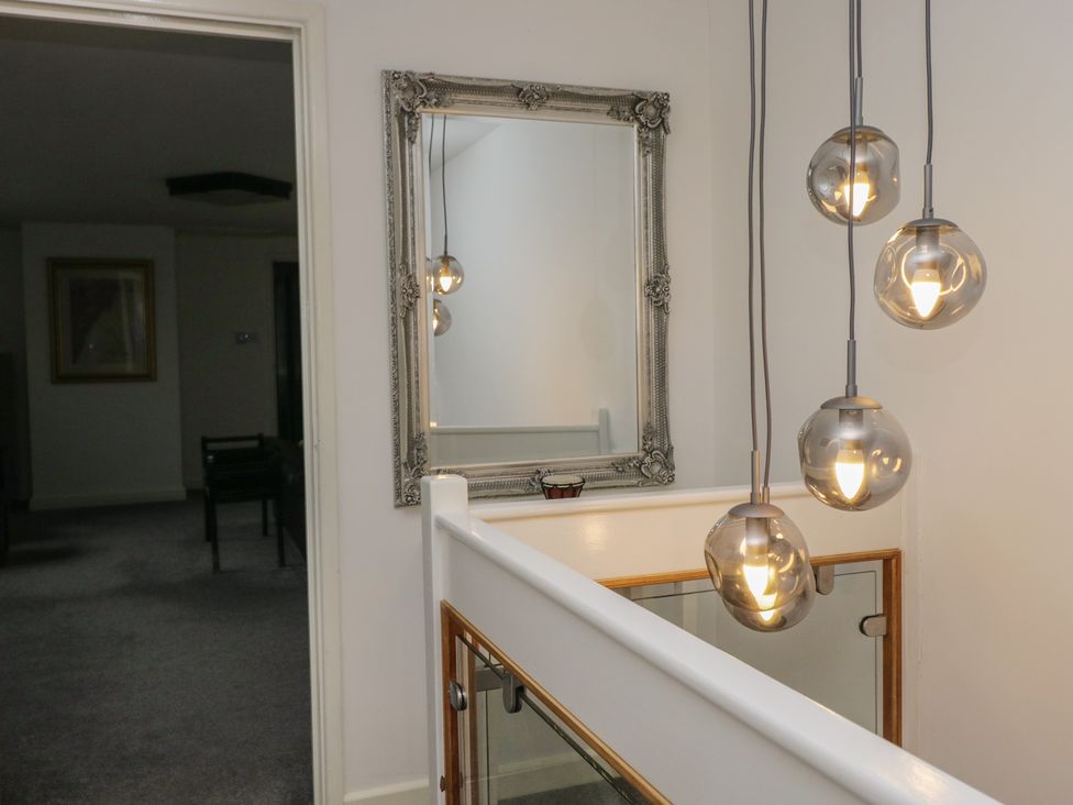 A hallway with a mirror and light fixture at Eildon Lodge in Gosforth