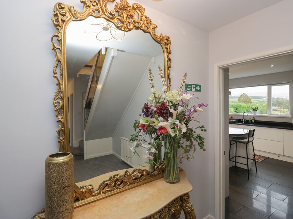 A hallway with a mirror and flowers at Eildon Lodge in Gosforth