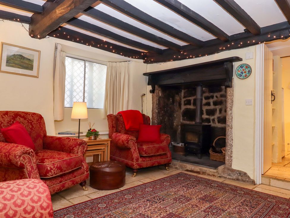 A living room with red armchairs and a fireplace at Fox Hat Cottage in Chagford