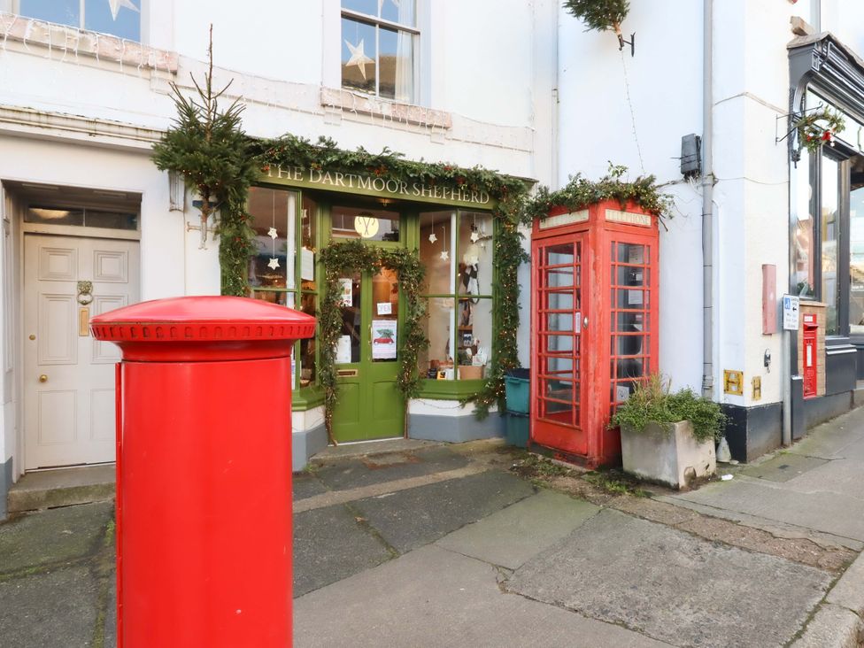 A shop front with a red post box and telephone box at Fox Hat Cottage in Chagford