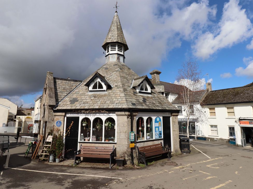 A building with a pointed roof and benches located at Fox Hat Cottage Chagford
