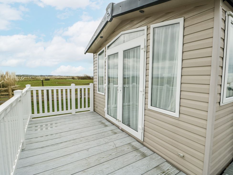 An outdoor area with a cabin and decking at Trewan Chalet Bryngwran near Rhosneigr