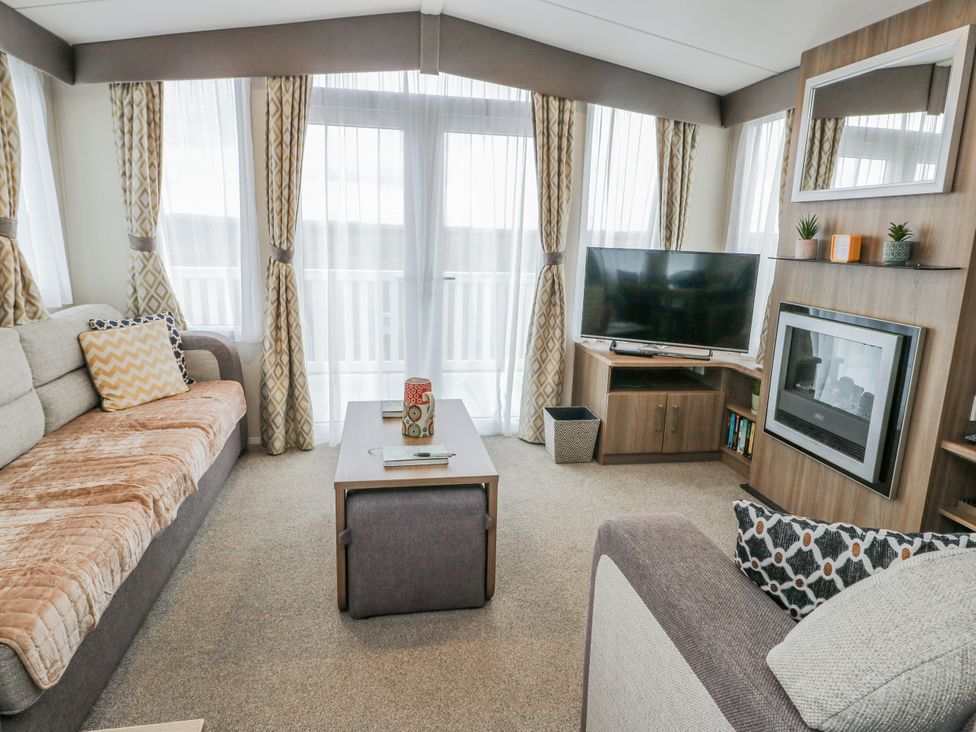A living room with a sofa, television, and coffee table at Trewan Chalet in Bryngwran near Rhosneigr