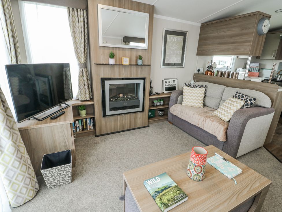 A living room with a fireplace and television at Trewan Chalet Bryngwran near Rhosneigr