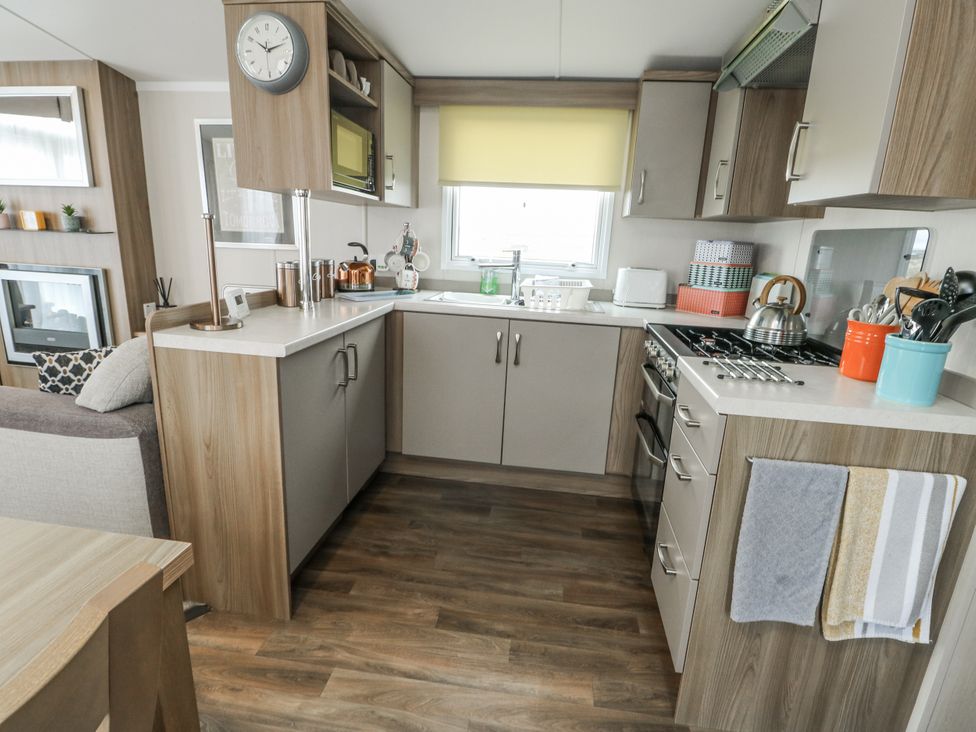 A kitchen with cabinets, stove, and sink at Trewan Chalet in Bryngwran near Rhosneigr