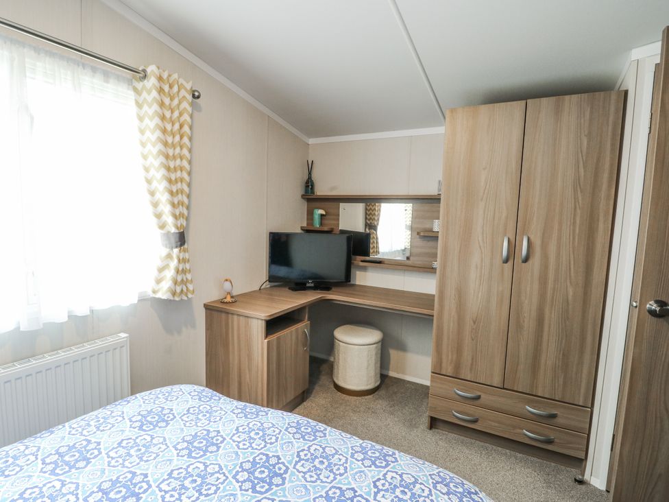 A bedroom with a bed and a desk at Trewan Chalet Bryngwran near Rhosneigr