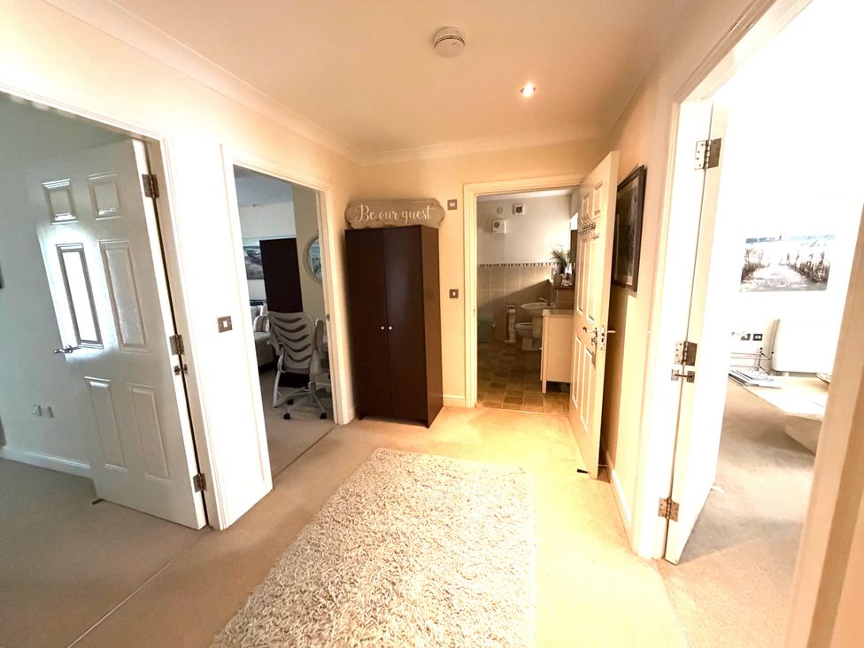 A hallway with a cabinet and multiple doorways at Apartment 1 in Middleton near Heysham