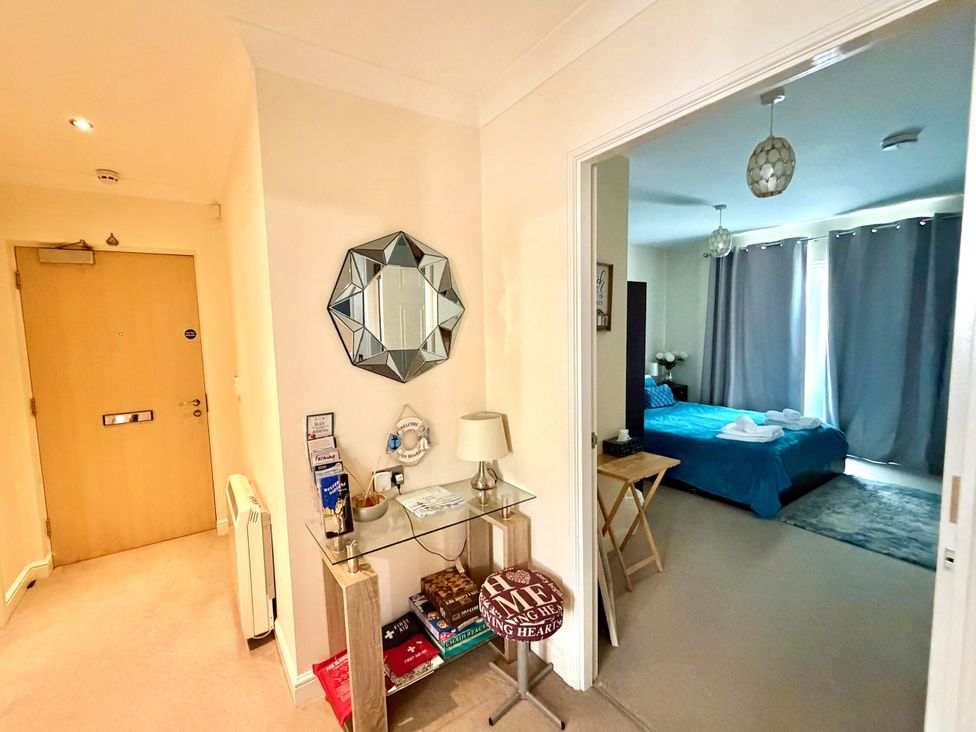 A hallway with a mirror and table leading to a bedroom at Apartment 1 Middleton near Heysham