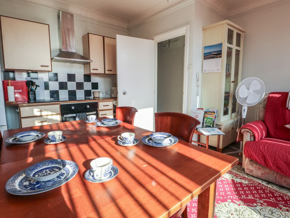 A dining room with a table set with dishes and a fan at Sylvian in Bexhill-On-Sea