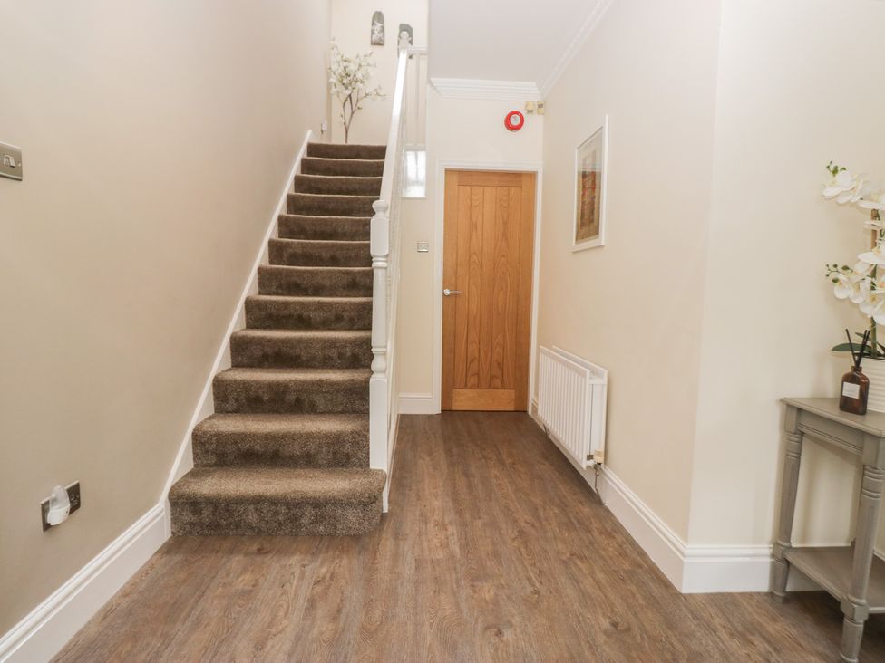 A hallway with a staircase and console table at Chestnuts Cottage in Windermere