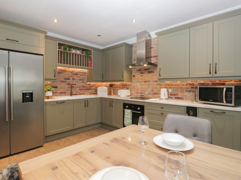 A kitchen with appliances and dining table at Chestnuts Cottage in Windermere