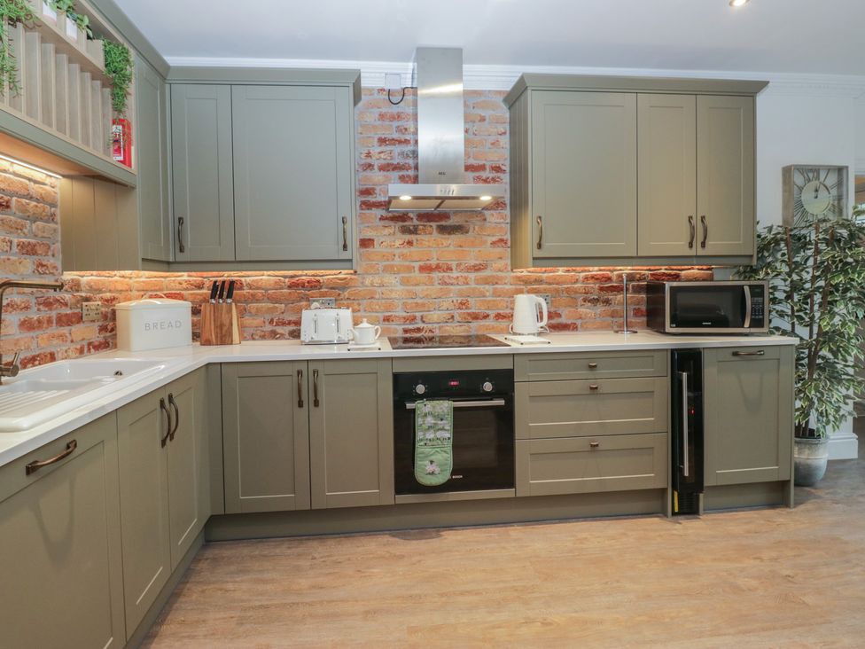 A kitchen with cabinets, sink, and appliances at Chestnuts Cottage in Windermere
