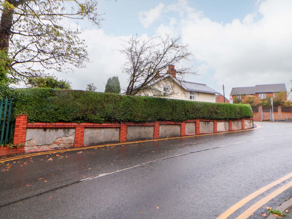 A road with a hedge and wall in front of a house at Bryn Offa cottage in Holywell