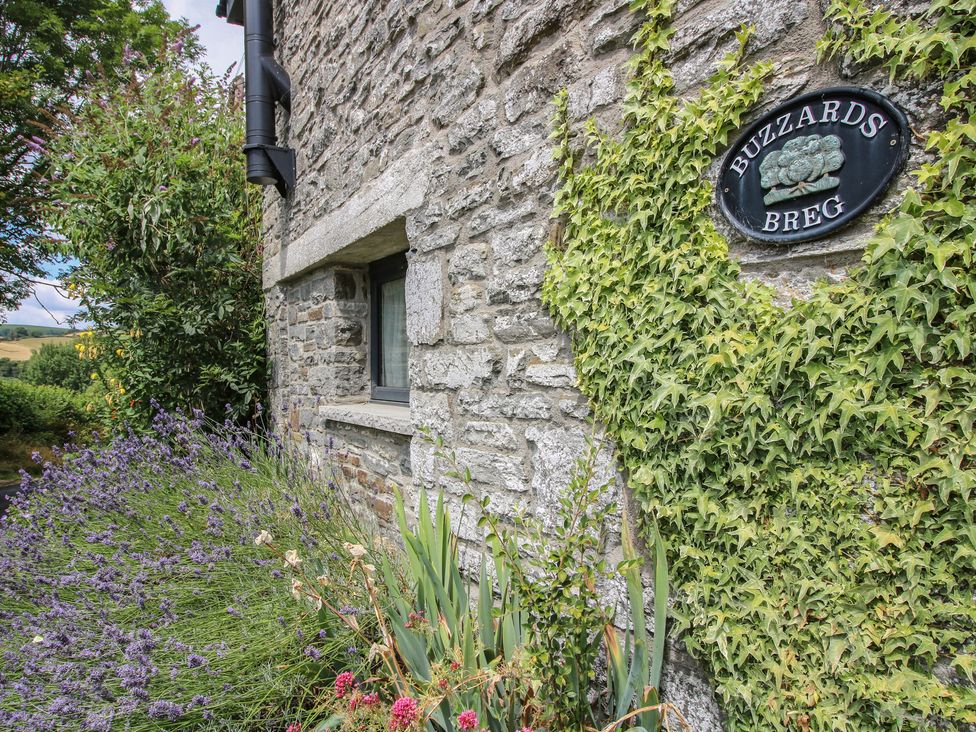 A stone wall with a house sign and plants at Buzzards Breg in Builth Wells