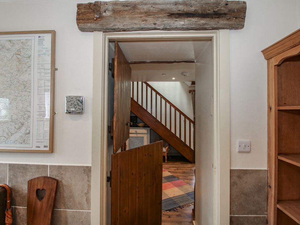 A hallway with a wooden door and staircase at Buzzards Breg in Builth Wells