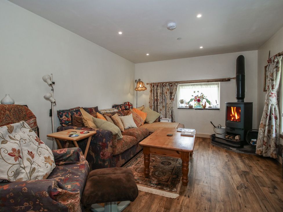 A living room with a sofa and wood stove at Buzzards Breg in Builth Wells