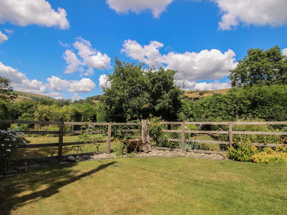 A garden with a fence and trees at Buzzards Breg in Builth Wells