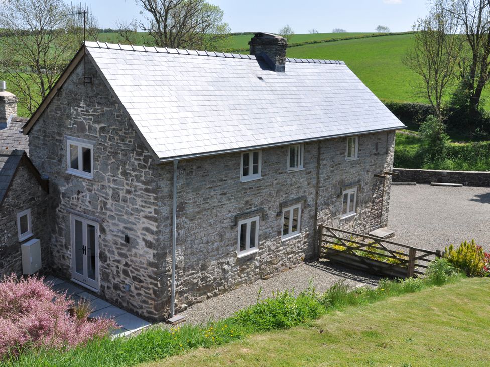 A stone house with a gravel driveway at Rockhill Farmhouse in Clun