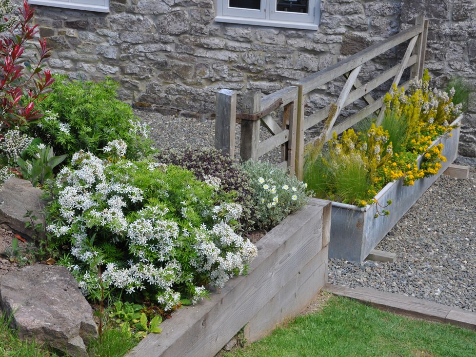 A garden with flowers and gravel at Rockhill Farmhouse in Clun