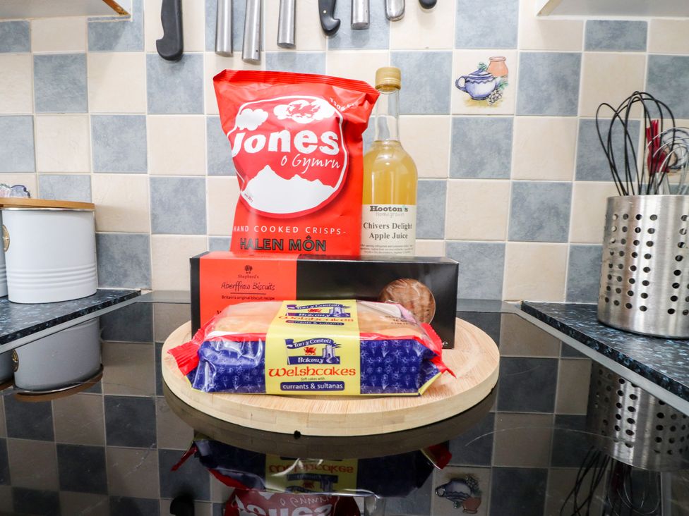 A kitchen countertop with snacks including crisps and apple juice at 3 Tai Newydd Llanfaelog near Rhosneigr
